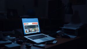 Een rommelig bureau met een oude laptop die YouTube-abonnementen beheert.